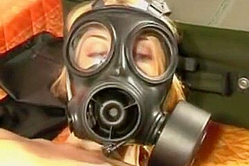 Blonde in gas mask on bed