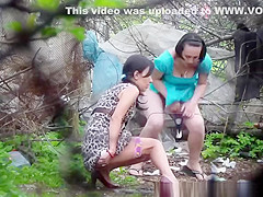 Two brunette women spied pissing outdoors